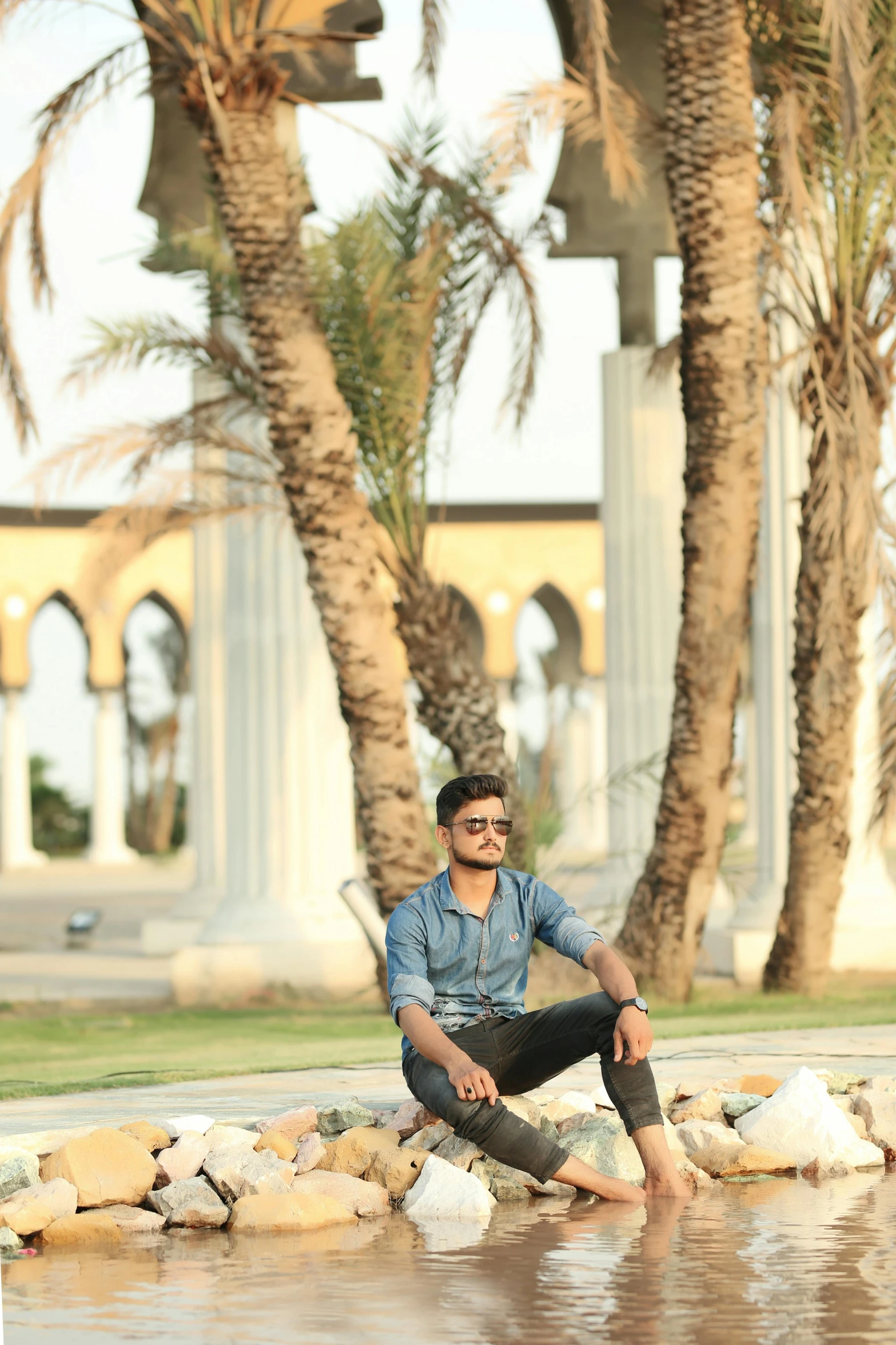 a man is sitting on a wall next to a tree