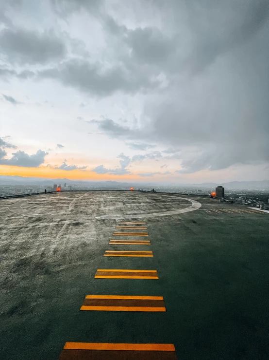 yellow painted roadway in field at sunset with cloudy sky