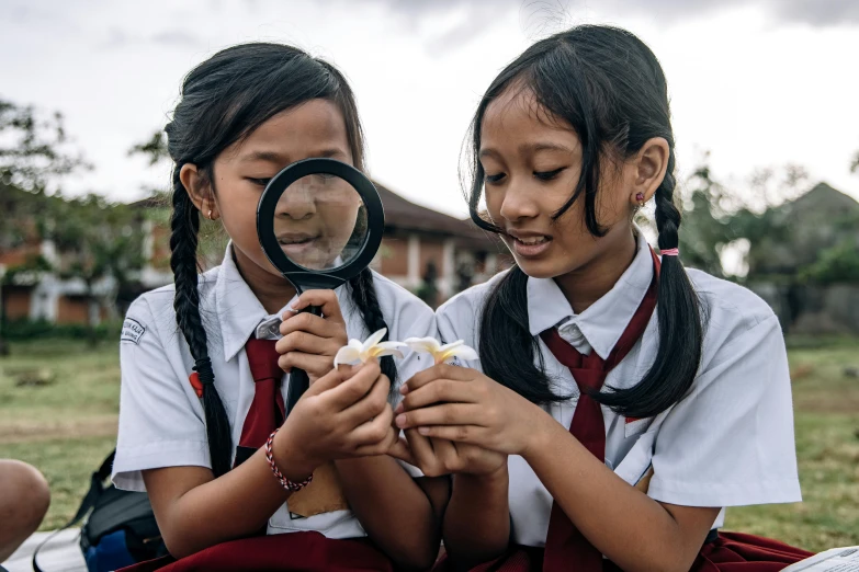 two girls who are looking through a magnifying glass