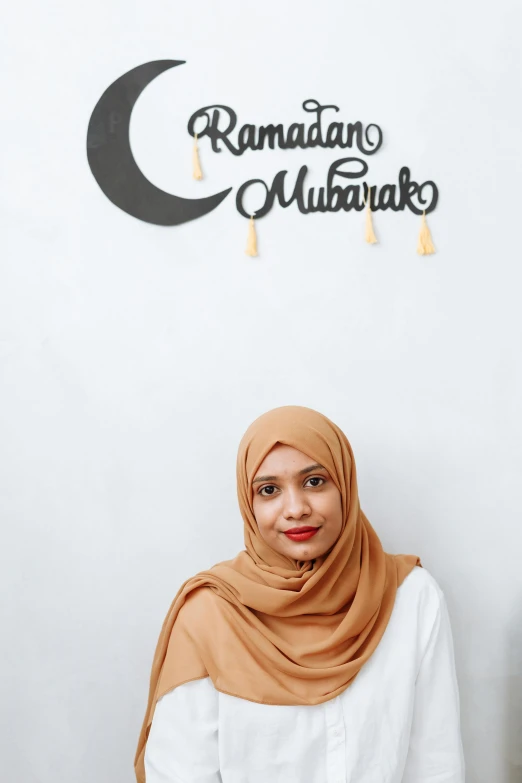 an oriental woman in an islamic outfit standing next to a raman mubarak wall sign