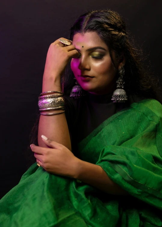 a young woman is dressed in a sari and holding her hand to her face