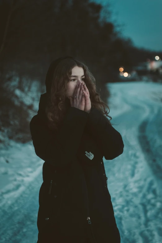 a woman is standing on a snowy road at night