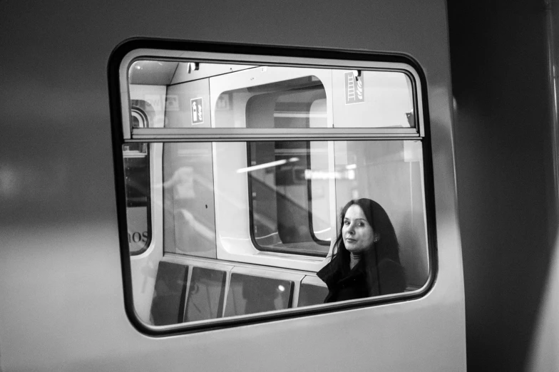 black and white po of woman looking out the window on a train