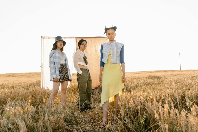 three people in sunglasses and dress walking through a field