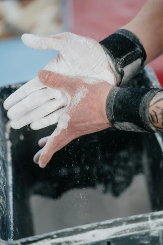 someones hands covered in flour on a shiny black bin