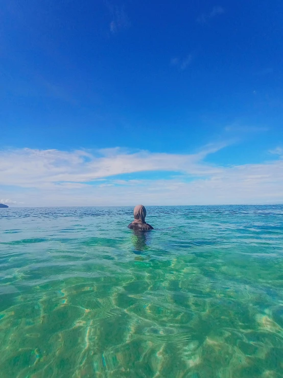 a man swimming in the ocean under a blue sky