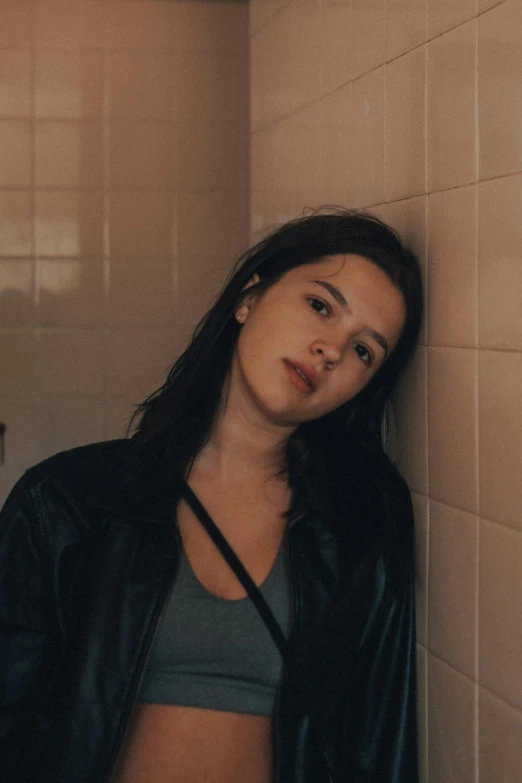 the young woman is standing in front of the tiled wall