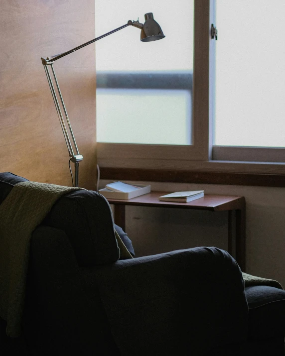 a dimly lit couch with a computer desk and window