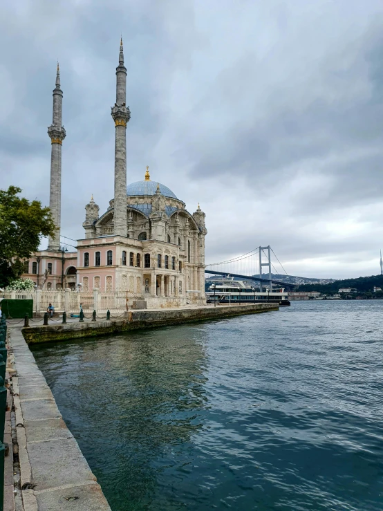 two towers on top of an old building next to a body of water