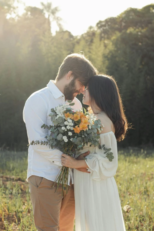 a man and woman smile as they kiss in a field