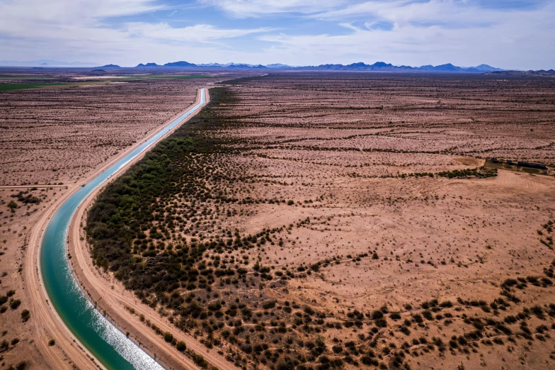 an aerial view of a desert with water and trees