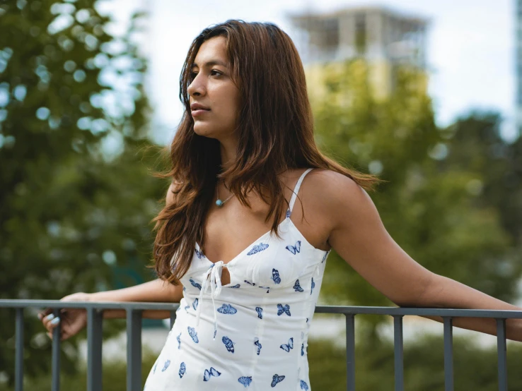 a woman stands on the balcony near trees