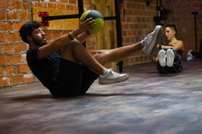 two people sitting on the floor with their feet up in front of the wall