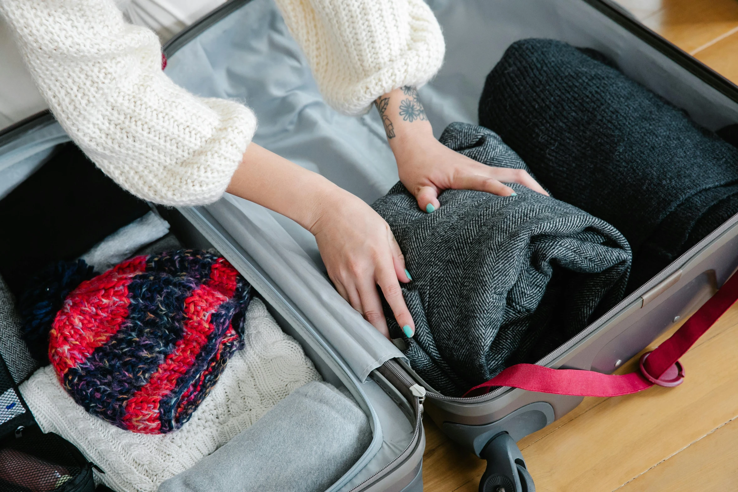 a woman putting in some clothing in her suit case