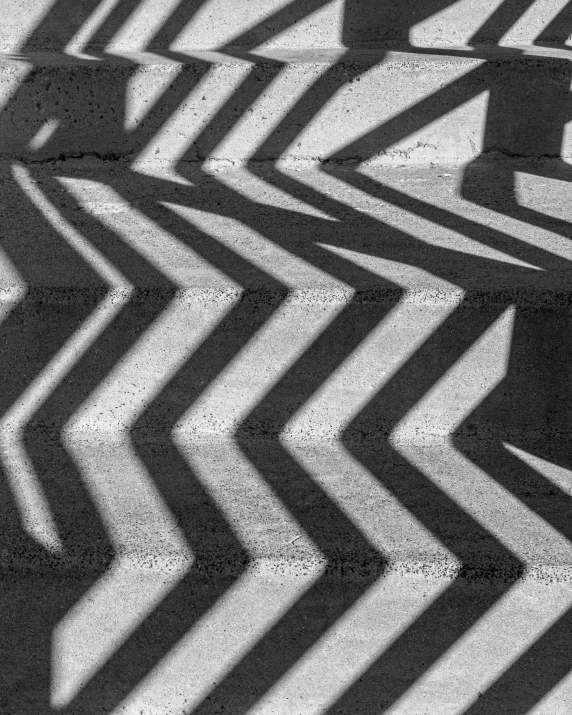 the shadow of many patterns on a sidewalk