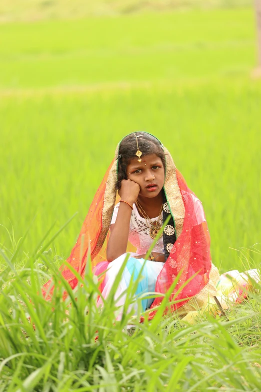 a girl sits in the middle of a large grassy field