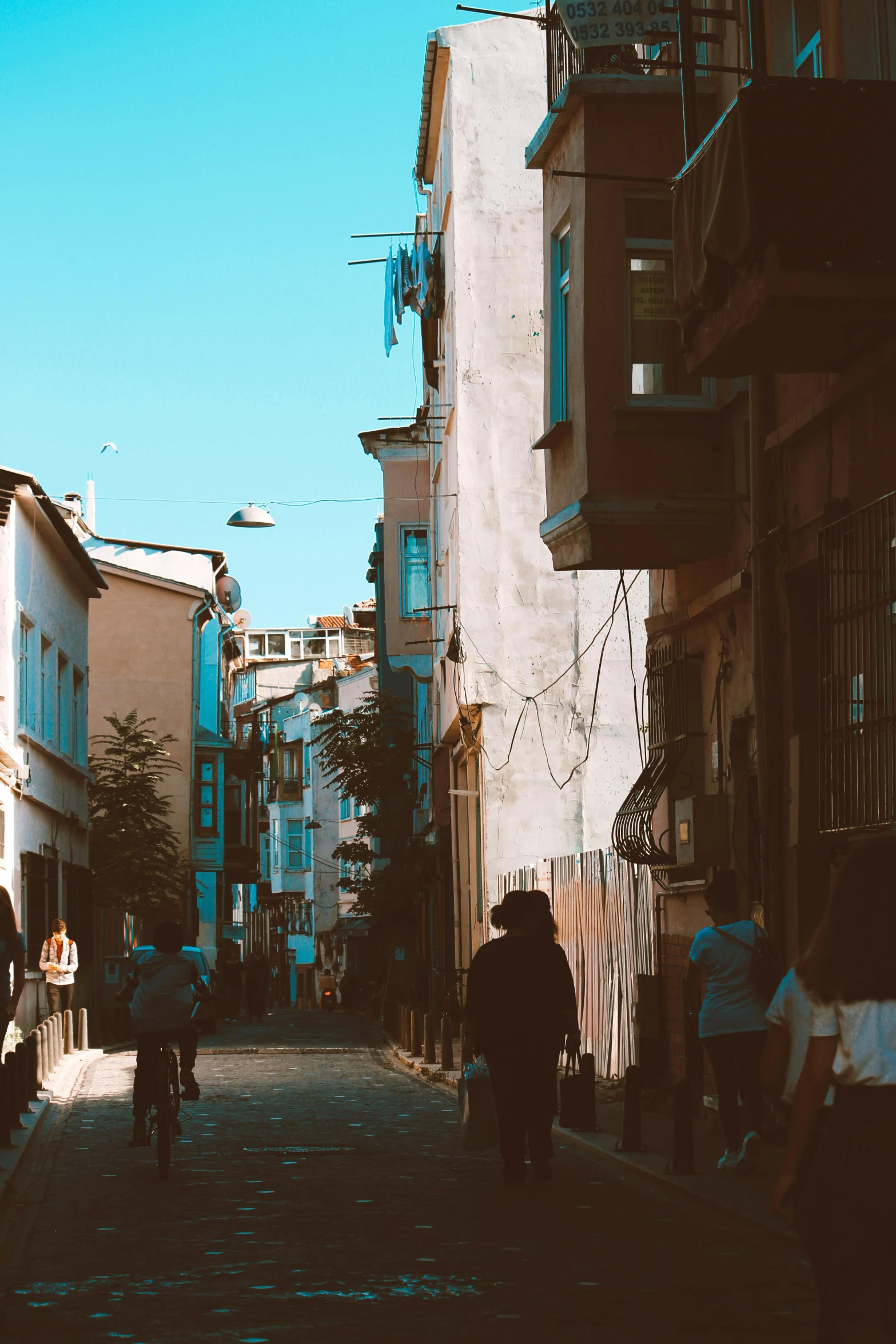 several people riding bicycles down an alleyway next to buildings