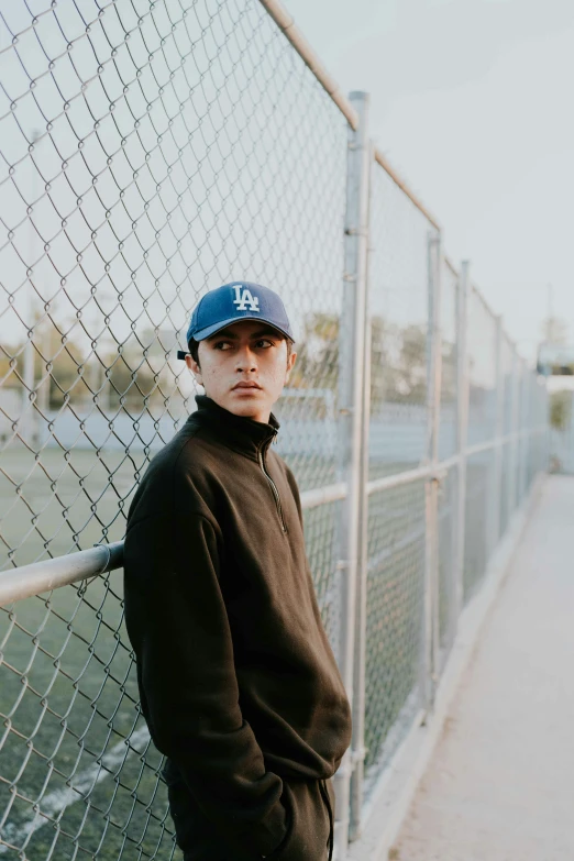 a man leaning on a fence with his hat in hand