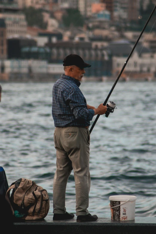 a man standing on the side of a body of water holding onto a fish hook