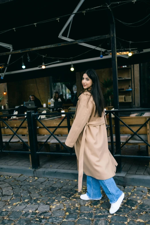 a young woman walking outside with a long coat on