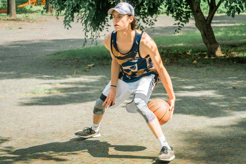 a young man holding a basketball on top of a lush green field