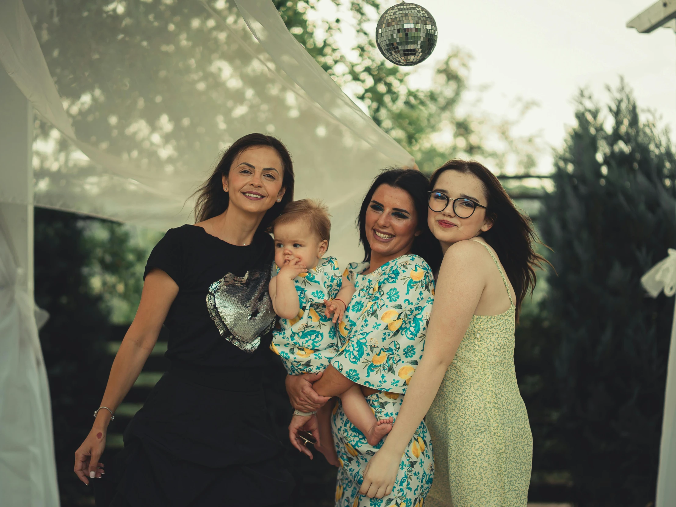 three women with baby posing in front of an umbrella