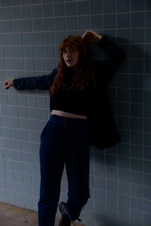 a woman leaning against a tiled wall with one foot on the wall