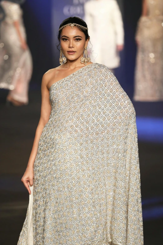 a woman wearing a large dress is walking down the runway