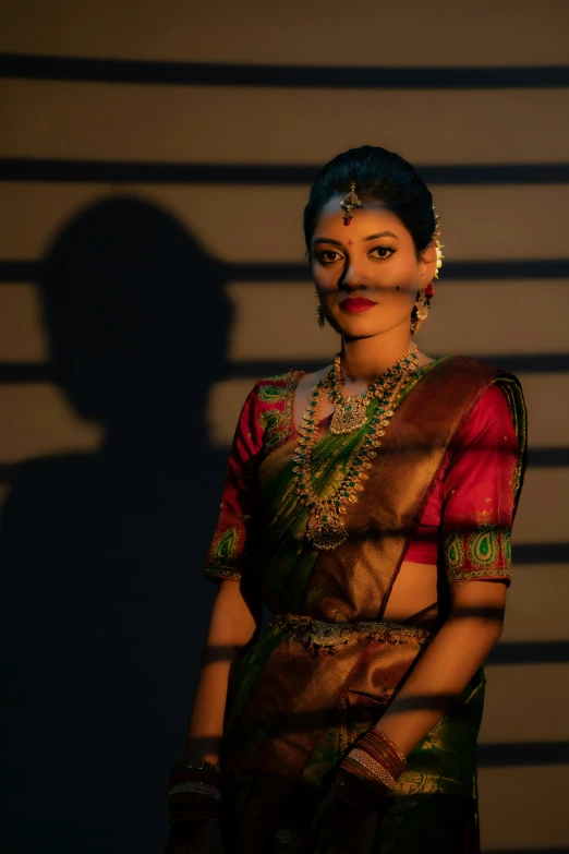 a woman wearing a green sari and posing in the shadow