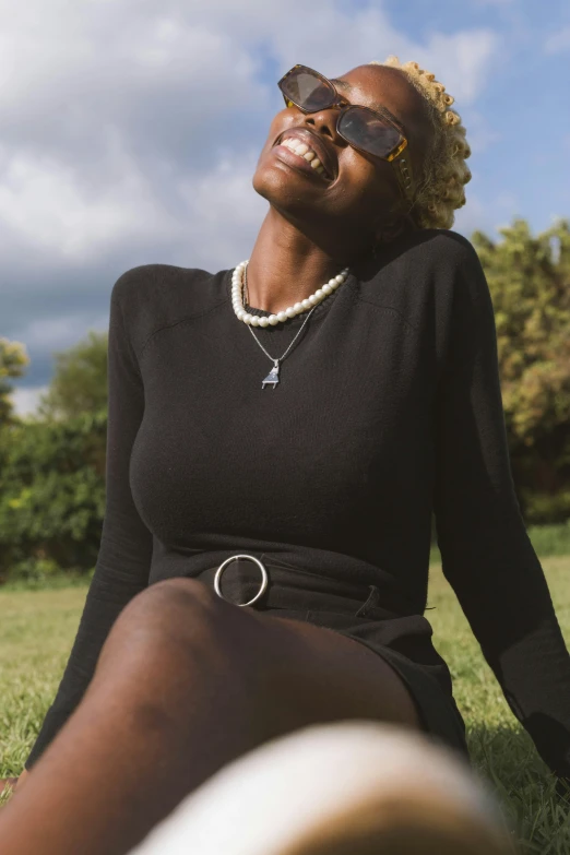 a woman smiles wearing sunglasses and a black top