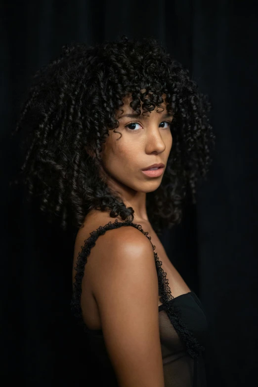 a woman with large curls is staring off to the side