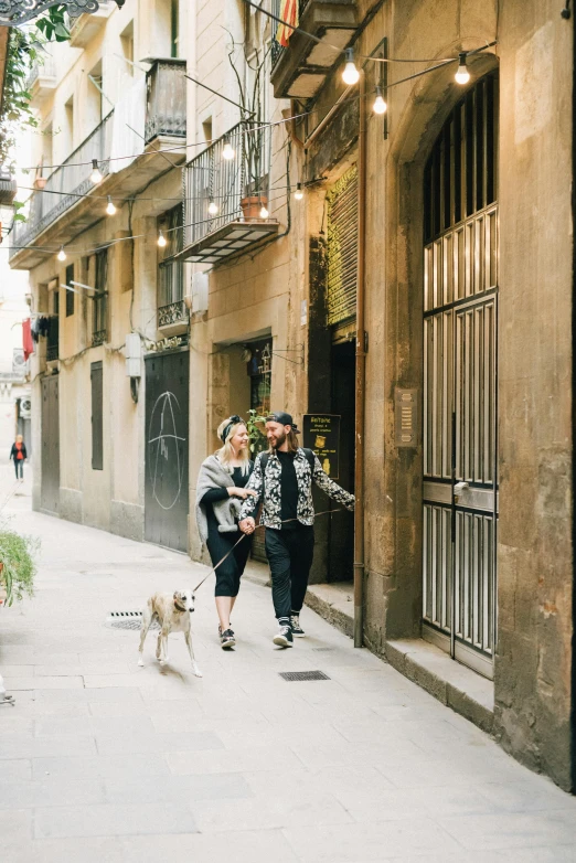 a man and a woman are walking down the street, both are walking their dog