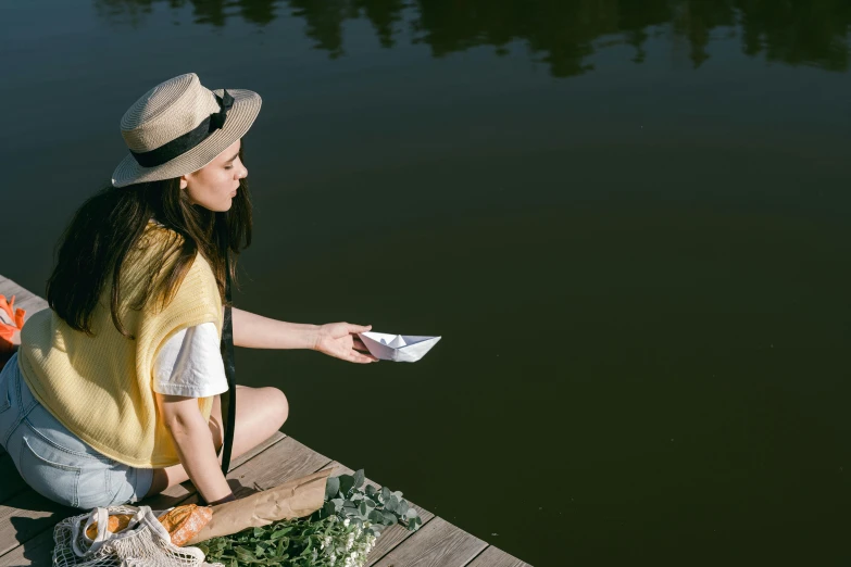 a woman on the edge of a lake, throwing a paper