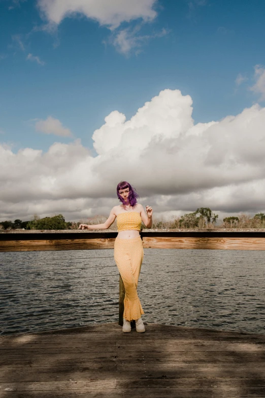 a woman dressed in yellow and standing near water