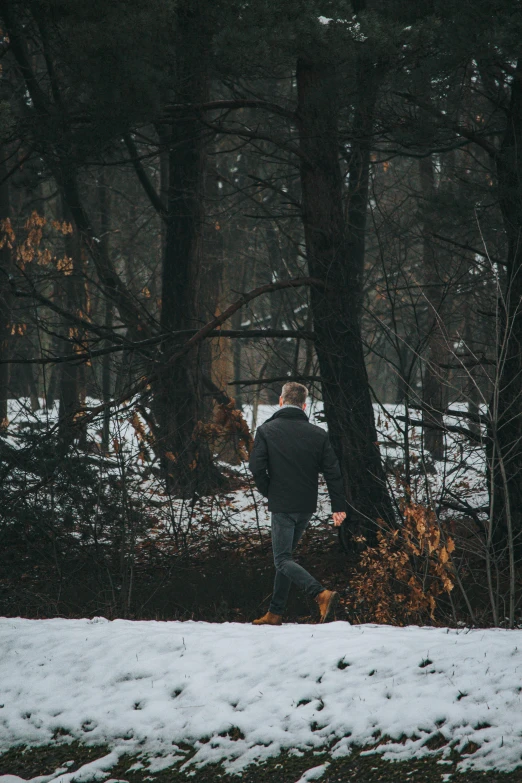 a man runs through the woods as snow falls