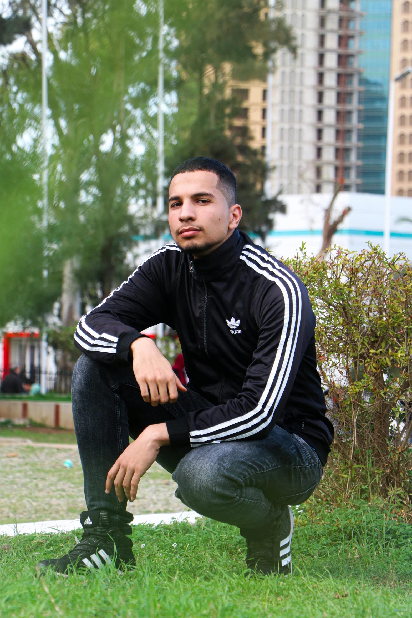 a man squatting on the grass with his hand on the ground