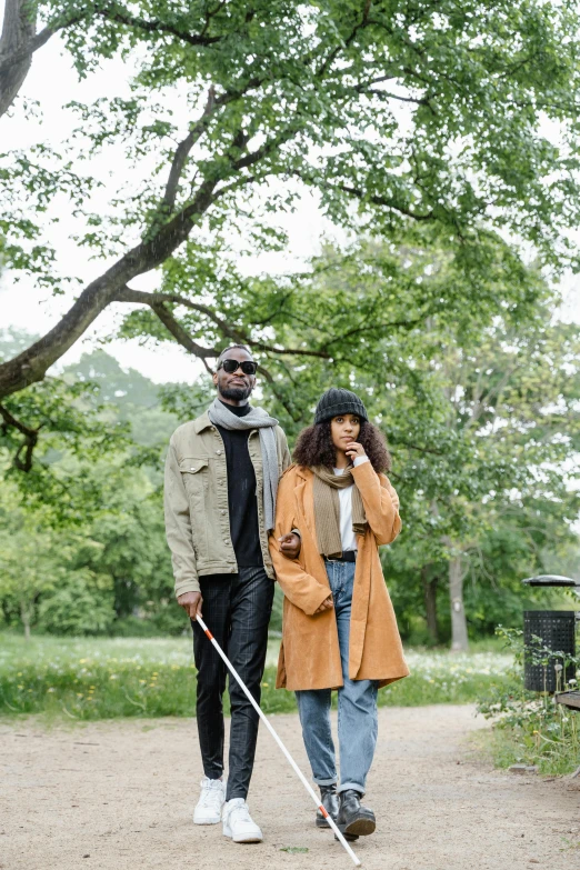 a woman holding a walking stick and a man walking by her on a path