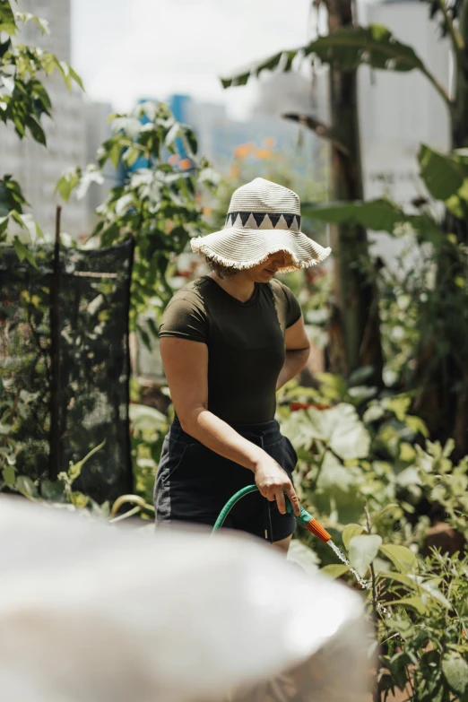 woman wearing a large white hat watering plants