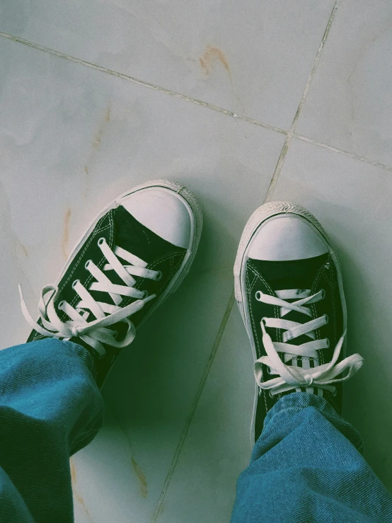 a person wearing blue jeans and black converses is standing