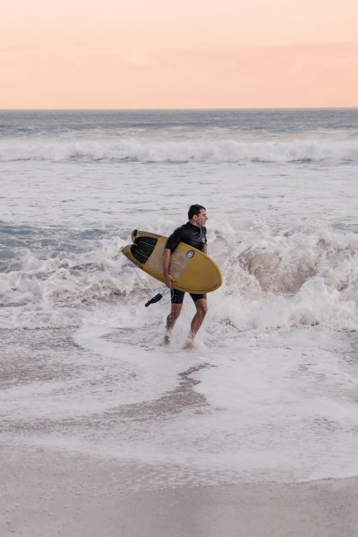a surfer carrying his board out to the ocean