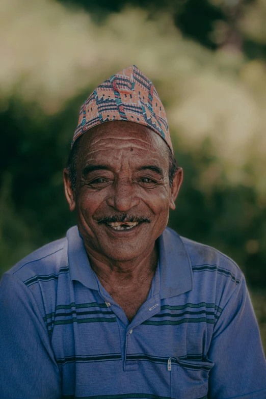 an elderly man smiling in a hat that looks like an indian