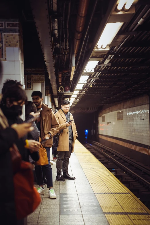 people in a subway station waiting on the platform for their train