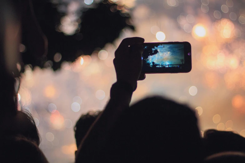 someone using their phone to take a picture of the fireworks