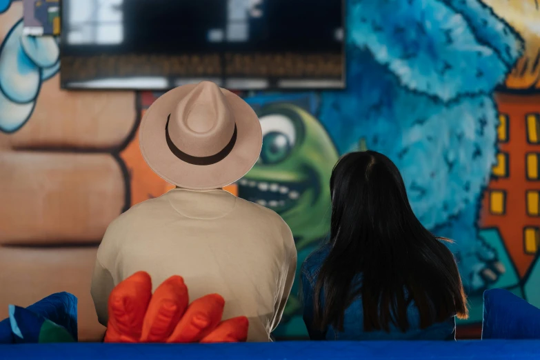 a man and woman sitting on the ground in front of a tv