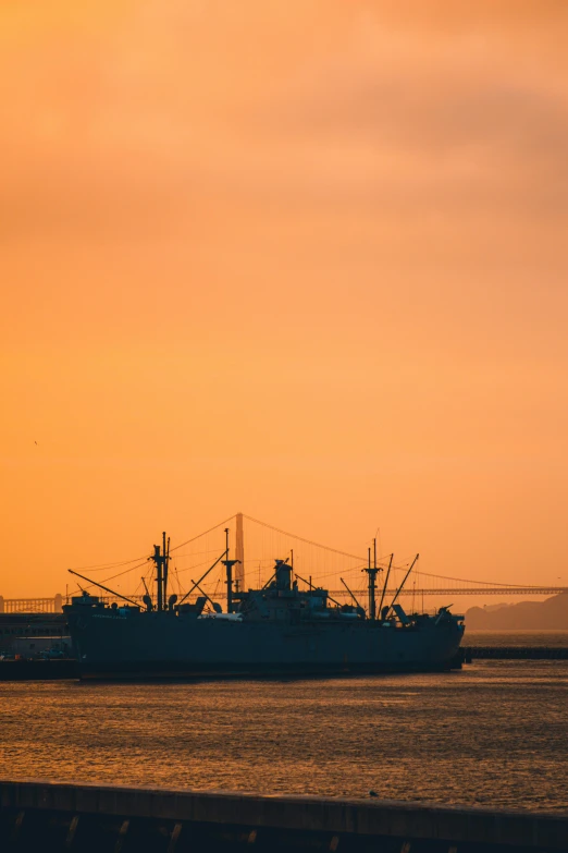 a ship at sea with two lights on the top and an orange sky