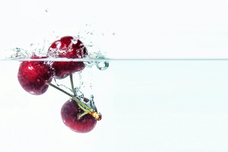 three cherries in water with splashing water