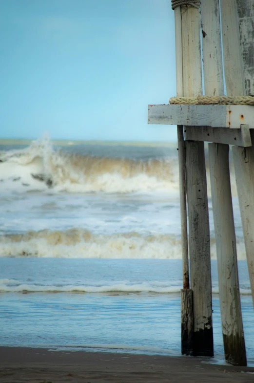 an ocean shore has a wooden bench near the beach