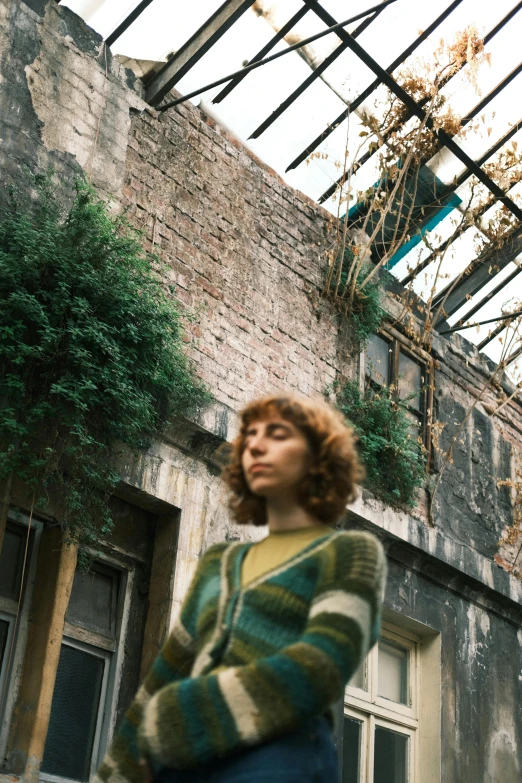 a woman walking by a building with ivy growing on the wall