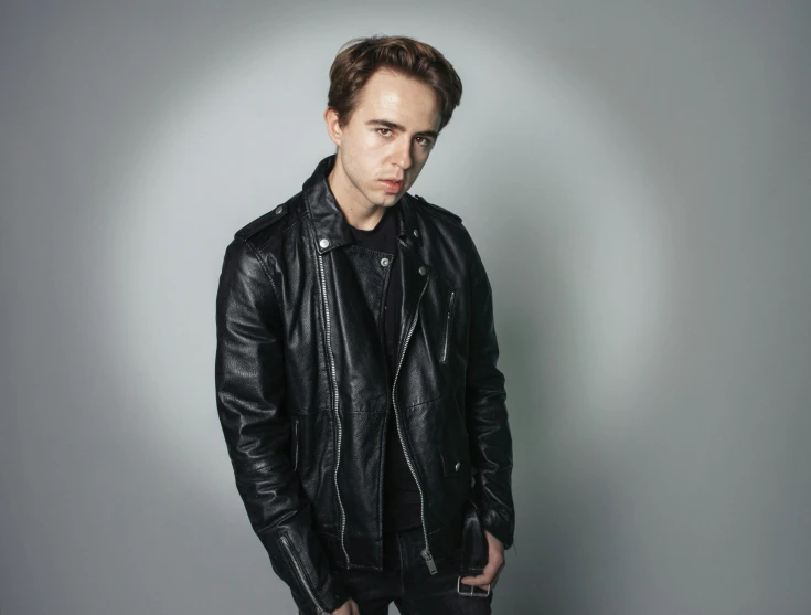 a young man is posing for a portrait in leather jacket