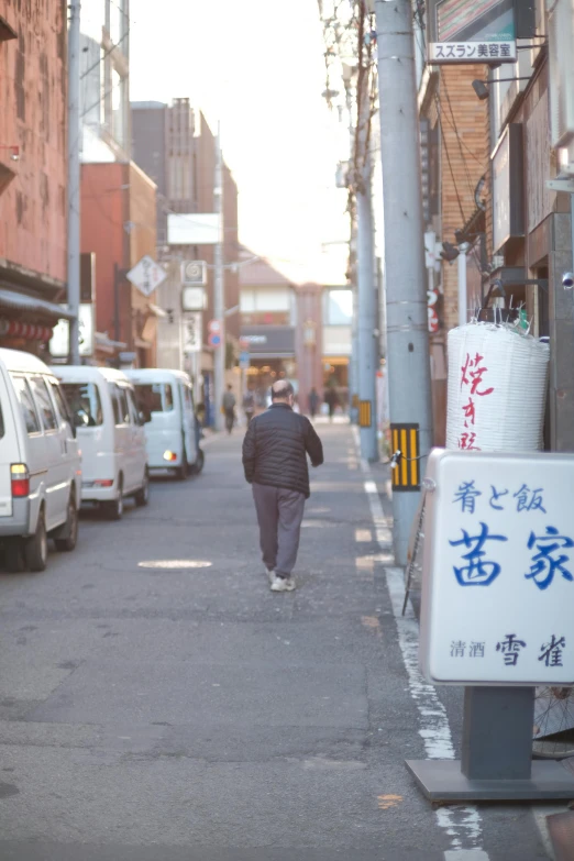 a man walks in the street carrying his cell phone